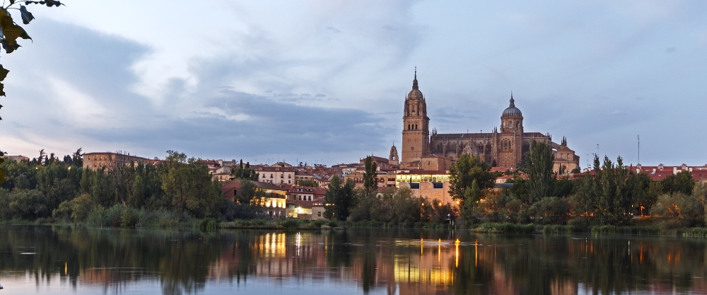 The New Cathedral and Old Cathedral of Salamanca, iconic monuments of Spanish historical heritage, seen from the banks of the River Tormes in one of Europe's oldest university cities.